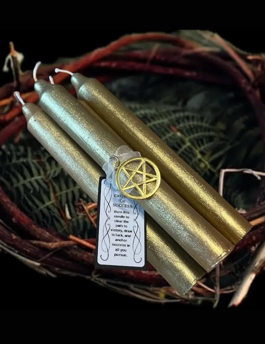 Gold and green taper candles with a pentacle charm and ritual card resting in a woven twig basket